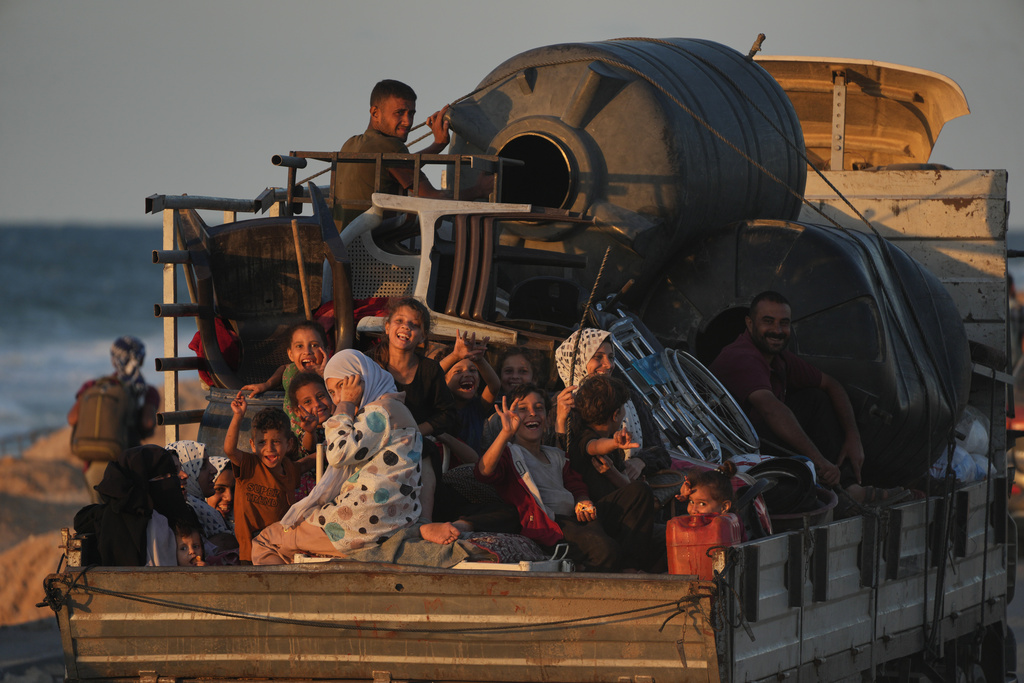 A displaced Palestinian family, rides on a truck loaded with water tanks, furniture and other belongings as they travel along the coastal road near Wadi Gaza in the central Gaza Strip, heading toward Gaza City, Friday, Oct. 10, 2025, after Israel and Hamas agreed to a pause in their war and the release of the remaining hostages. (AP Photo/Abdel Kareem Hana)
