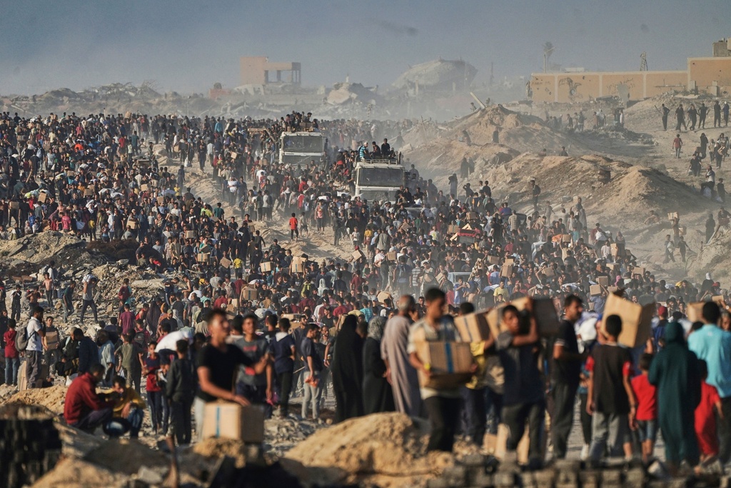 People carry sacks and boxes of food and humanitarian aid that was unloaded from a World Food Program convoy that had been heading to Gaza City in the northern Gaza Strip, Monday, June 16, 2025. (AP Photo/Jehad Alshrafi)