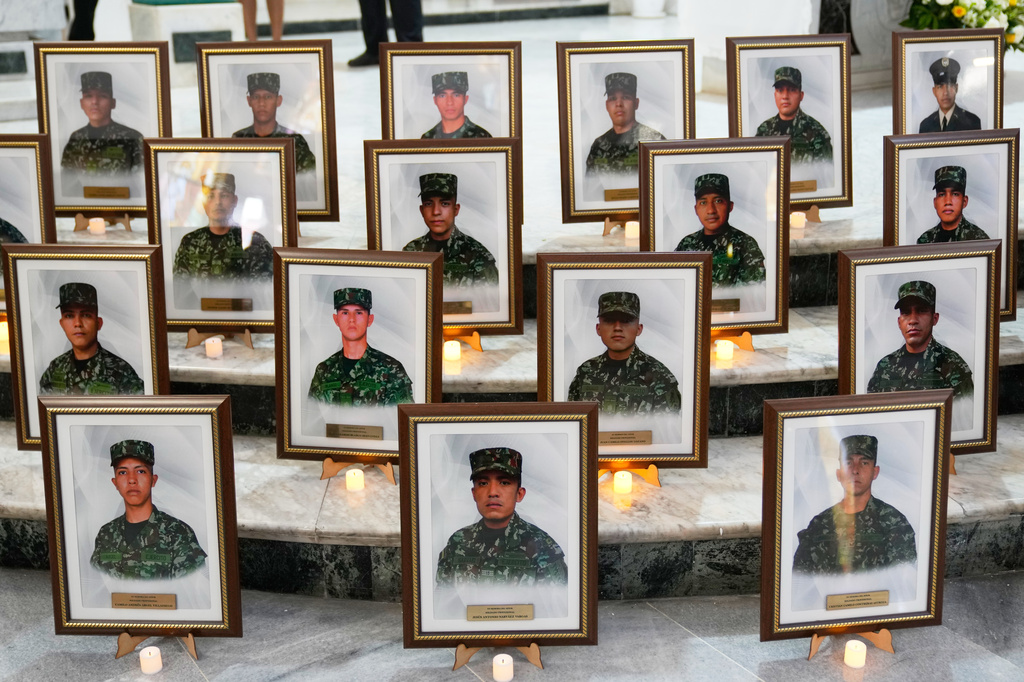FILE - Photos of soldiers who died on a military cargo plane that crashed in Puerto Leguizamo, are arranged on the steps of an altar before the start of a memorial Mass at a military base church in Bogota, Colombia, March 27, 2026. (AP Photo/Fernando Vergara, File)