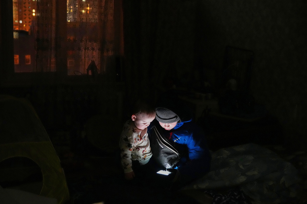 Daniil Dolotov, 11, plays on a phone with his brother Bohdanchyk, 18 months, in their apartment during a power outage caused by Russia’s repeated air strikes on the country’s power grid, in Kyiv, Ukraine, Monday, Feb. 2, 2026. (AP Photo/Sergey Grits)