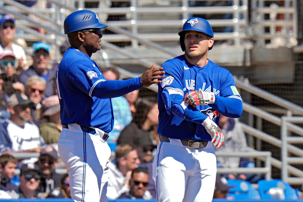 Toronto Blue Jays' Daulton Varsho, right, celebrates his triple off New York Yankees pitcher Will Warren with third base coach Carlos Febles during the first inning of a spring training baseball game Tuesday, Feb. 24, 2026, in Dunedin, Fla. (AP Photo/Chris O'Meara)
