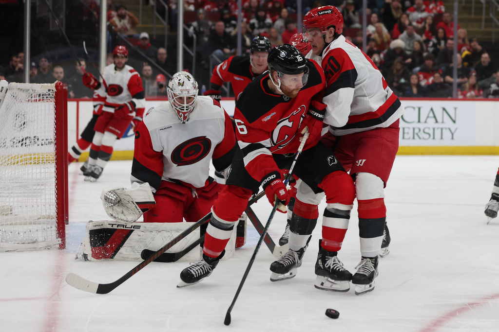 New Jersey Devils right wing Connor Brown (16) looks to pass the puck around Carolina Hurricanes left wing Eric Robinson (50) in the second period of an NHL hockey game, Sunday, Jan. 4, 2026, in Newark, N.J. (AP Photo/Heather Khalifa)