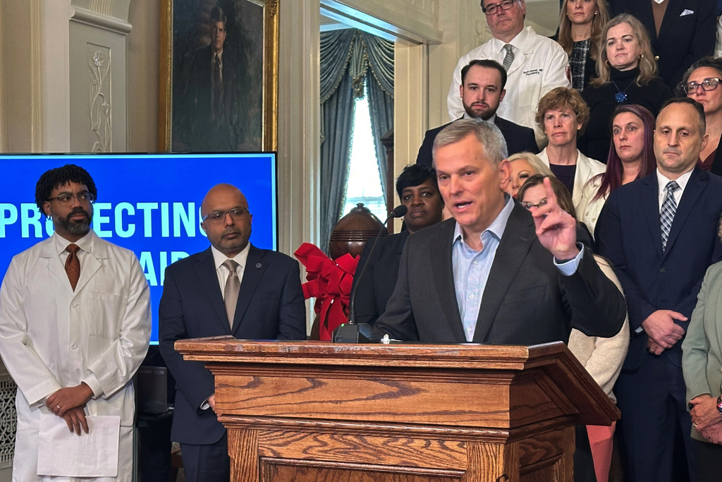 North Carolina Gov. Josh Stein, right, speaks while Dr. Benjamin Simmons with the North Carolina Academy of Family Physicians, far left, and state Health and Human Services Secretary Dr. Dev Sangvai listen to Stein discussing the restoration of Medicaid reimbursement rates to pre-October levels at an Executive Mansion news conference on Wednesday, Dec. 10, 2025 in Raleigh, N.C. (AP Photo/Gary D. Robertson)