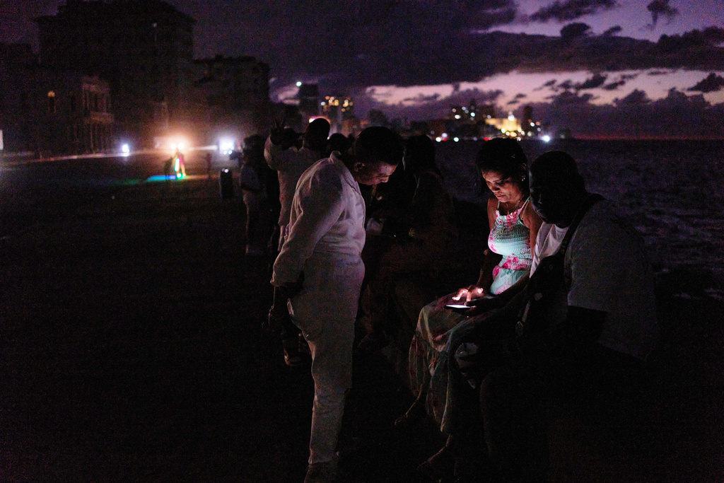 People spend the night in the dark on the Malecon during a blackout in Havana, Cuba, Saturday, March 21, 2026. (AP Photo/Ramon Espinosa)