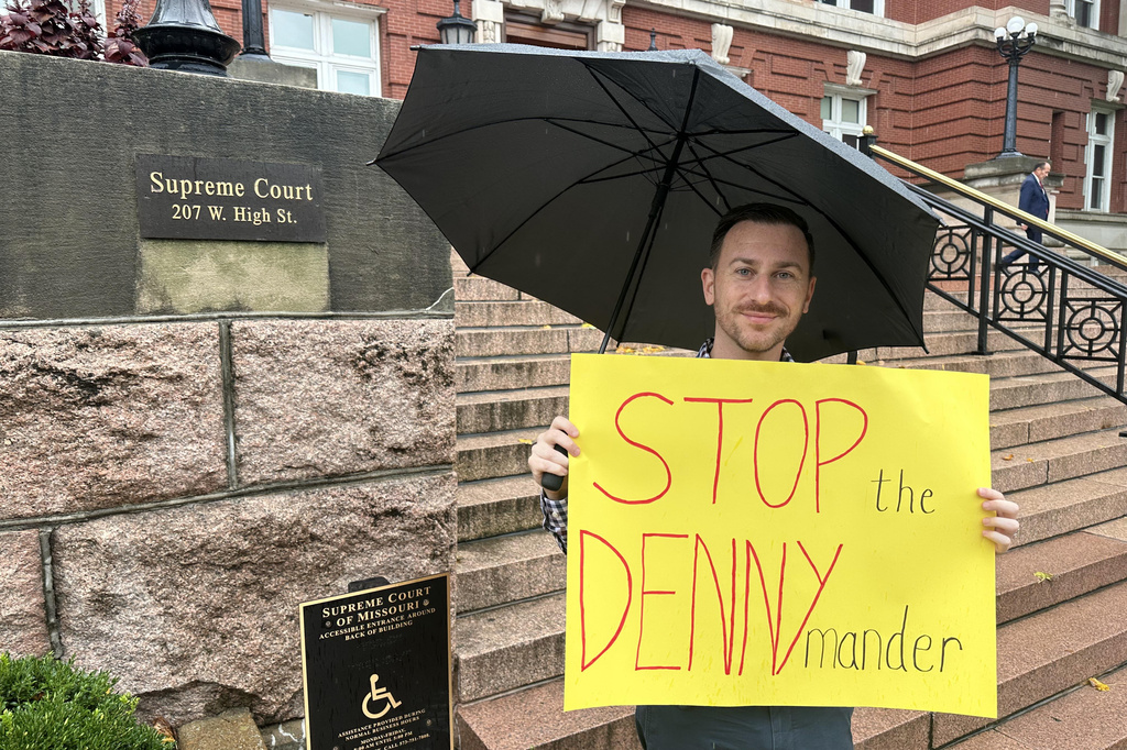 This photo taken with a smartphone shows Keith Rose holding a sign opposed to new Missouri congressional districts supported by Secretary of State Denny Hoskins outside the Missouri Supreme Court in Jefferson City, Mo., Thursday, Sept. 10, 2026. (AP Photo/David A. Lieb)