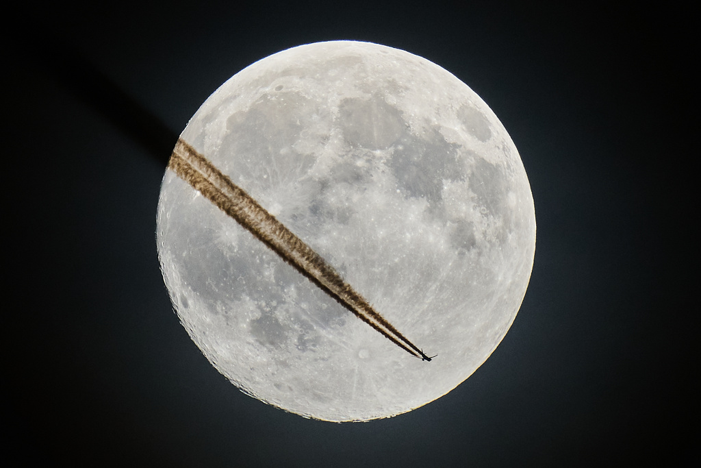 An aircraft passes the moon over Frankfurt, Germany, Tuesday, Nov. 4, 2025. (AP Photo/Michael Probst)