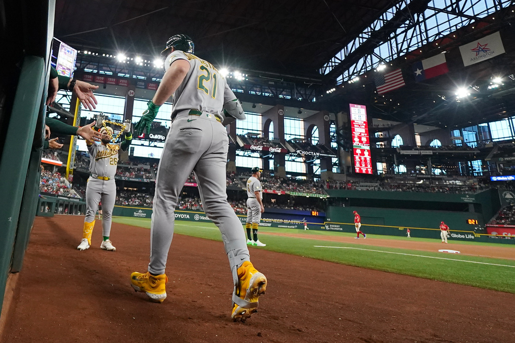 Athletics' Tyler Soderstrom (21) is greeted near the dugout by Carlos Cortes (26) after hitting a solo home run off Texas Rangers starting pitcher Nathan Eovaldi, not visible, during the first inning of a baseball game Friday, April 24, 2026, in Arlington, Texas. (AP Photo/Julio Cortez)