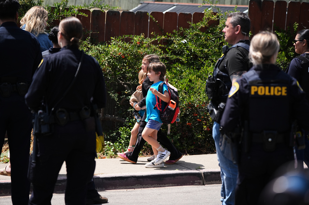 Children hold hand as they walk near the scene of a shooting outside the Islamic Center of San Diego Monday, May 18, 2026, in San Diego. (AP Photo/Gregory Bull)