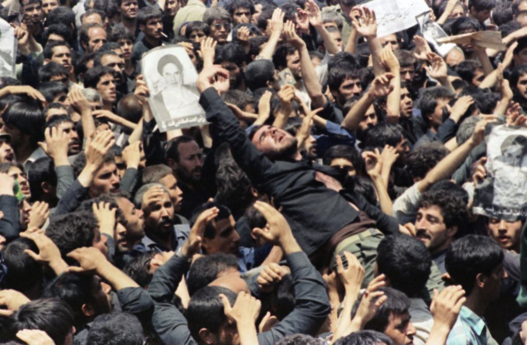 FILE - An Iranian mourner goes into a frenzy just after the body of the Ayatollah Khomeini was removed from Beheshte Zahra Cemetery in Tehran, June 6, 1989. The burial was delayed when thousands of mourners crowded the imam's body in an effort to touch their leader. (AP Photo/Greg English, File)