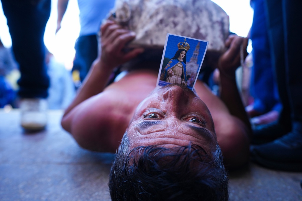 FILE - A pilgrim crawls on his back toward the altar at the Virgin of Lo Vásquez Sanctuary, holding a prayer card in his mouth of the Virgin Mary invoking the Immaculate Conception as part of a vow he made in gratitude for her intercession, in Valparaíso, Chile, Dec. 8, 2025. (AP Photo/Esteban Felix, File)