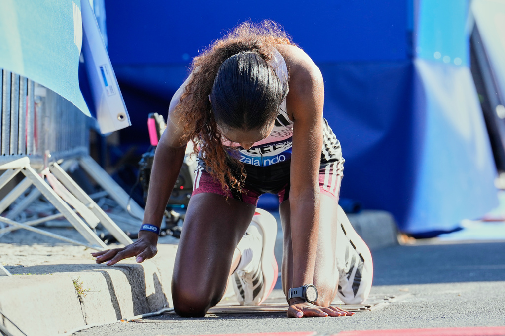 Ethiopia's Tigist Assefa kneels on the ground after winning he Berlin Marathon in Berlin, Germany, Sunday, Sept. 27, 2026. (AP Photo/Ebrahim Noroozi)