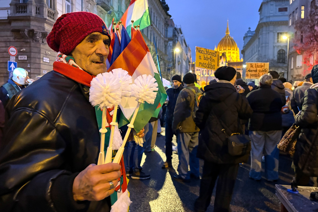 A man holds flags and toilet brushes at a protest called against a Hungarian government minister for comments he made about the Roma minority, in Budapest, Hungary, Saturday, Jan. 31, 2026. (AP Photo/Justin Spike)