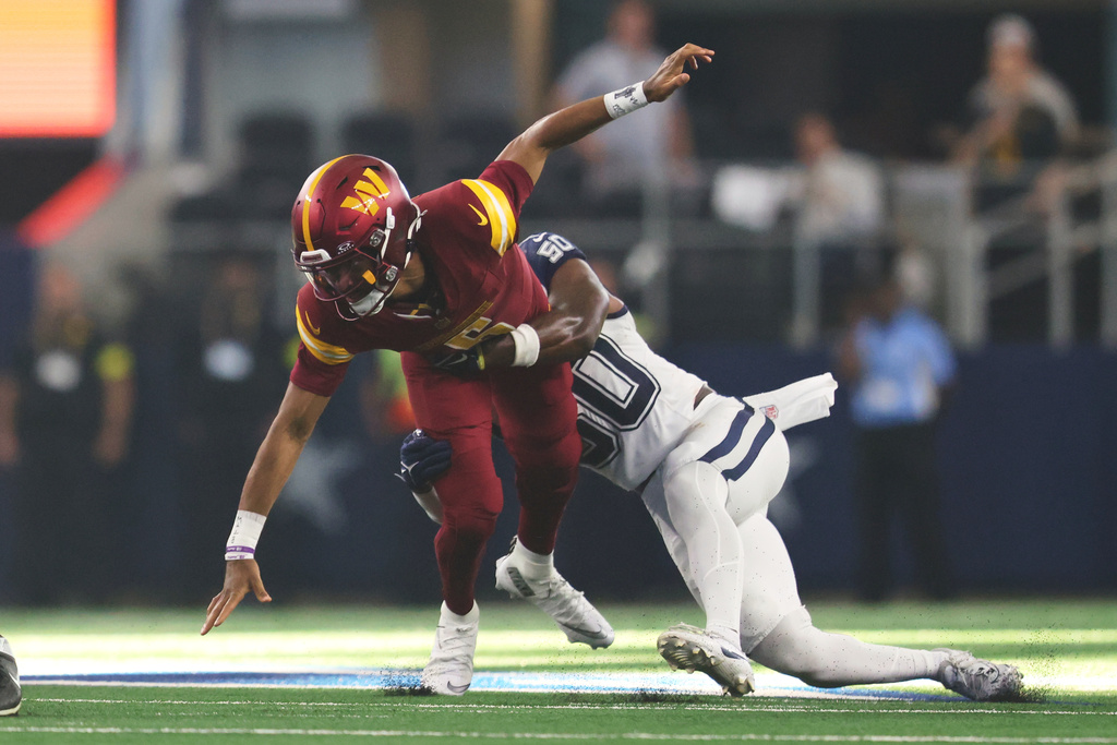 Washington Commanders quarterback Jayden Daniels, left, is pulled down by Dallas Cowboys linebacker Shemar James after fumbling the ball during the second half of an NFL football game Sunday, Oct. 19, 2025, in Arlington, Texas. (AP Photo/Gareth Patterson)