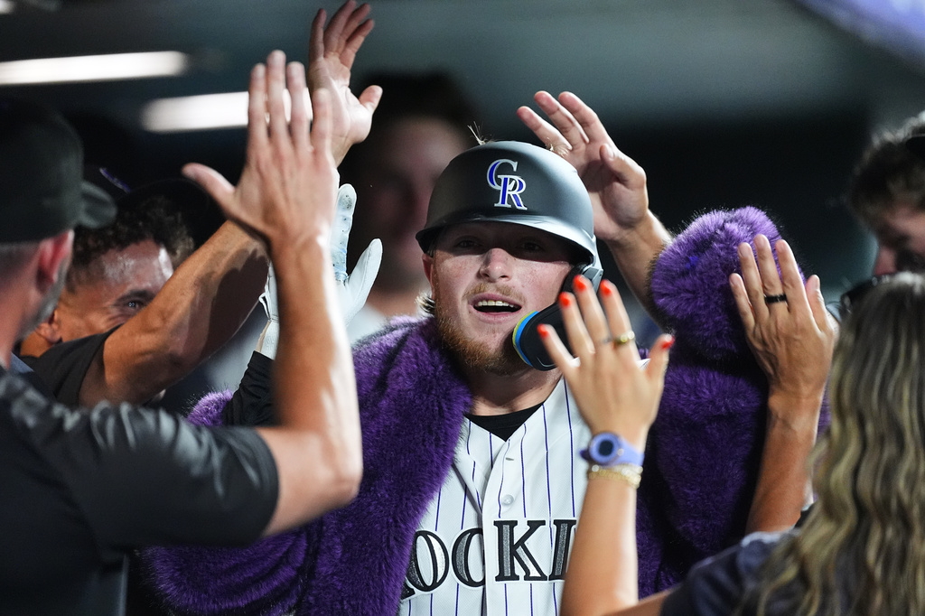 Colorado Rockies' Hunter Goodman is congratulated as he returns to the dugout after hitting a solo home run off Washington Nationals relief pitcher Clayton Beeter in the eighth inning of a baseball game Tuesday, July 21, 2026, in Denver. (AP Photo/David Zalubowski)