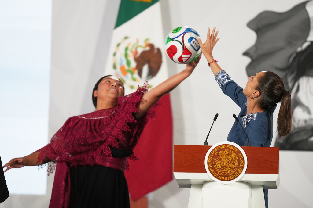 Mexican President Claudia Sheinbaum, right, and amateur soccer player Yolett Cervantes reach to catch a soccer ball during a ceremony distributing tickets to the opening match of the 2026 FIFA World Cup, at the president's daily news conference at the National Palace in Mexico City, Friday, May 29, 2026. (AP Photo/Fernando Llano)