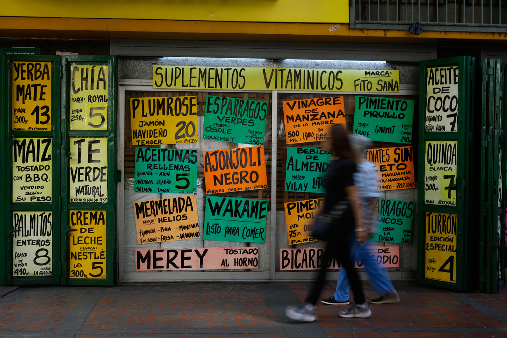 Pedestrians walk past a supermarket in Caracas, Venezuela, Tuesday, Jan. 6, 2026. (AP Photo/Matias Delacroix)