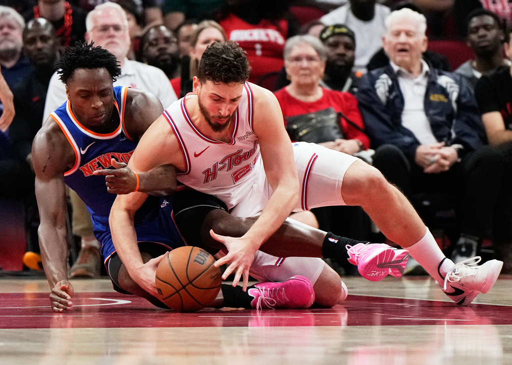 New York Knicks forward Og Anunoby and Houston Rockets center Alperen Sengun (28) reach for a loose ball during the first half of an NBA basketball game in Houston, Tuesday, March 31, 2026. (AP Photo/Ashley Landis)