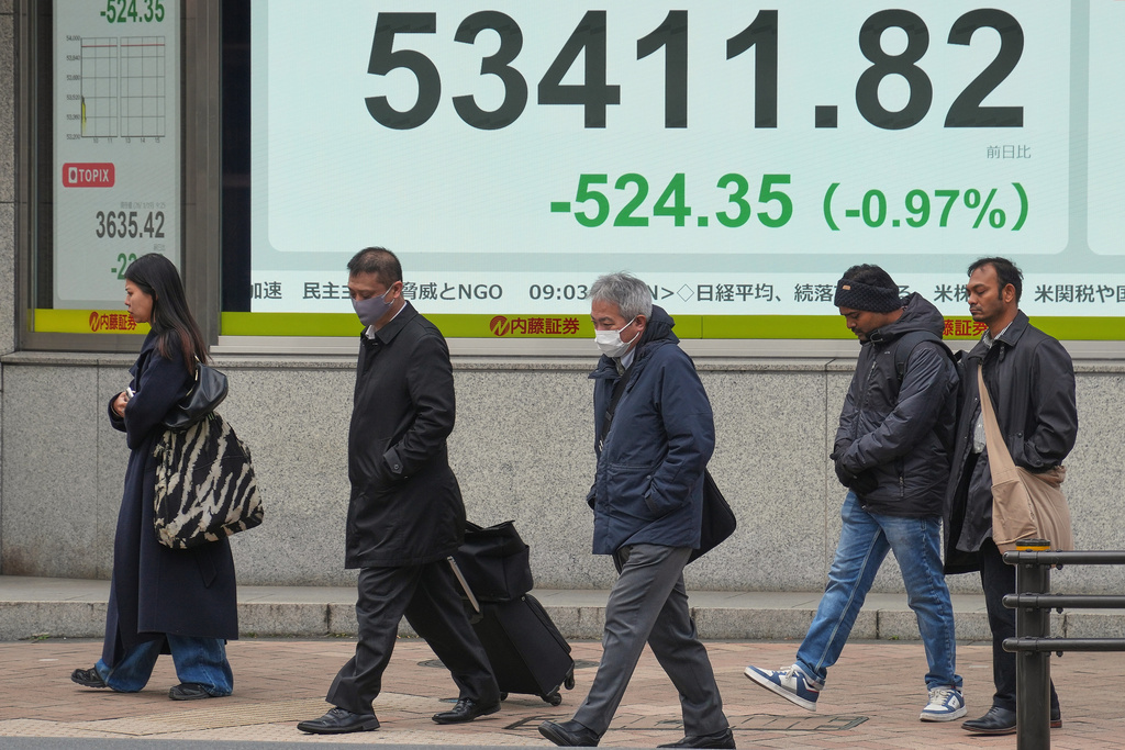 People walk in front of an electronic stock board showing Japan's Nikkei index at a securities firm Monday, Jan. 19, 2026, in Tokyo. (AP Photo/Eugene Hoshiko)