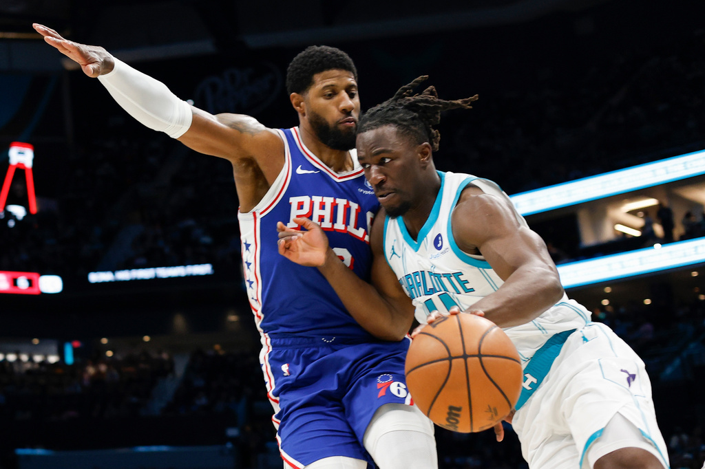 Charlotte Hornets guard Sion James, right, drives the baseline against Philadelphia 76ers forward Paul George during the first half of an NBA basketball game in Charlotte, N.C., Saturday, March 28, 2026. (AP Photo/Nell Redmond)