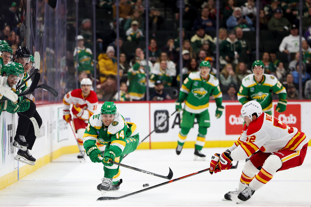 Minnesota Wild center Joel Eriksson Ek (14) knocks the puck away from Calgary Flames defenseman Mackenzie Weegar (52) for an assist on an empty-net goal during the third period of an NHL hockey game Sunday, Nov. 9, 2025, in St. Paul, Minn. (AP Photo/Ellen Schmidt)
