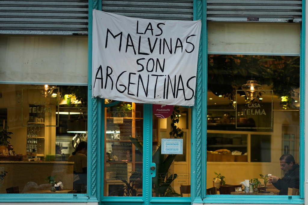 A man sits at a restaurant displaying a banner reading "The Malvinas are Argentine," referring to the Falkland Islands, also known as Malvinas, in Buenos Aires, Argentina, Monday, July 27, 2026. (AP Photo/Natacha Pisarenko)