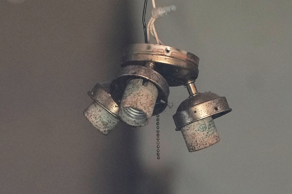 A hanging light fixture is seen through a broken window in a home where authorities say they removed 16 children and arrested four adults in Hamden, Ohio, Wednesday, July 1, 2026. (AP Photo/Carolyn Kaster)