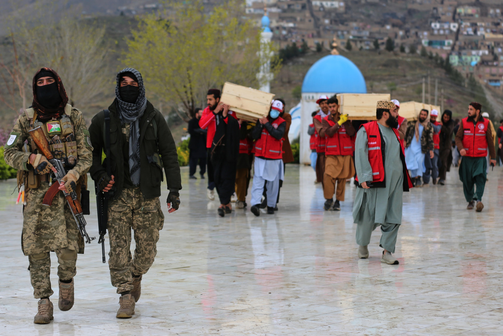 Taliban security personnel guard as people carry the remains of victims of a Monday airstrike on a drug rehabilitation hospital, ahead of the burials Wednesday, March 18, 2026, Kabul, Afghanistan. (AP Photo/Siddiqullah Alizai)