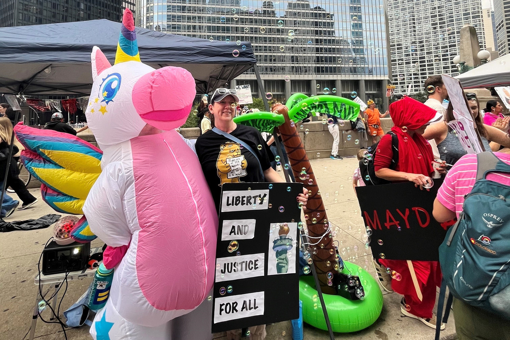 In this photo provided by Ian Vandawalker, Kristen Vandawalker, left, poses for a photo in her "pegacorn" inflatable costume at the "No Kings" event in Chicago, Saturday, Oct. 18, 2025. (Ian Vandawalker via AP)