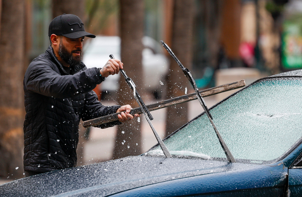 Nick Leon from Colorado knocks ice off his car in San Antonio, Texas, on Sunday morning, Jan. 25, 2026. He came to San Antonio after visiting Austin to get away of the ice storm. (Andrew J. Whitaker/The San Antonio Express-News via AP)