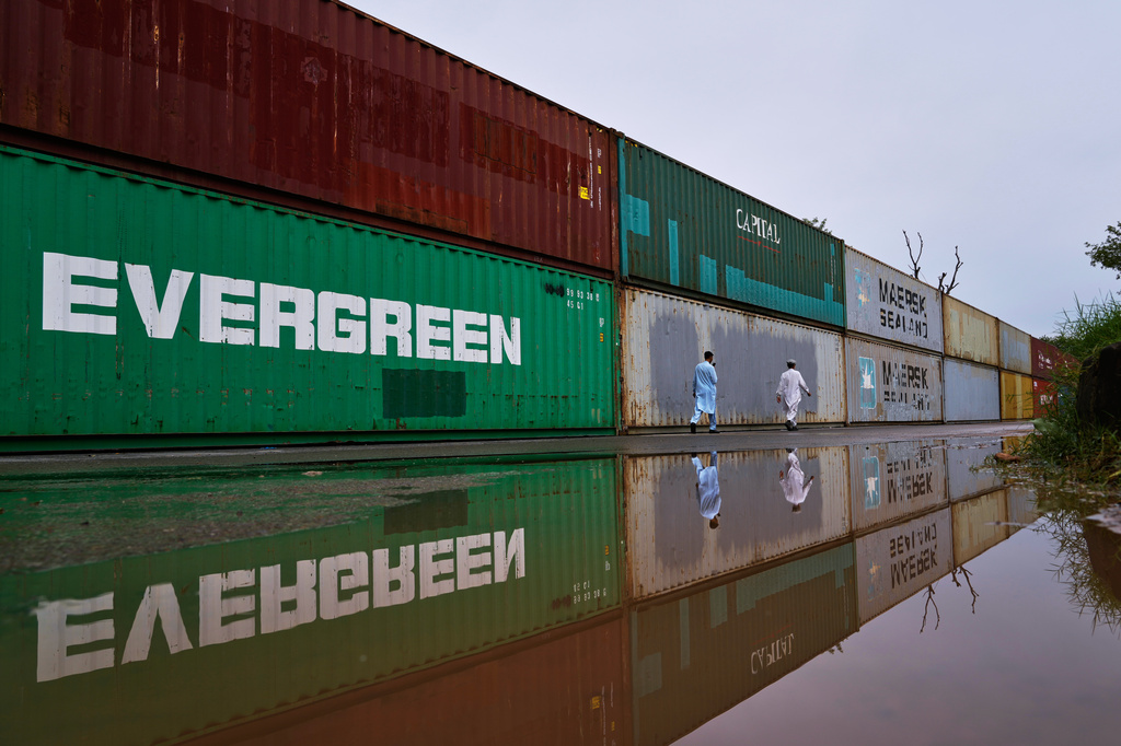 Residents walk past shipping containers placed by authorities to seal off an area ahead of a plan protest march by the supporters of imprisoned former Prime Minister Imran Khan demanding his release, in Islamabad, Pakistan, Monday, Sept. 28, 2026. (AP Photo/Anjum Naveed)