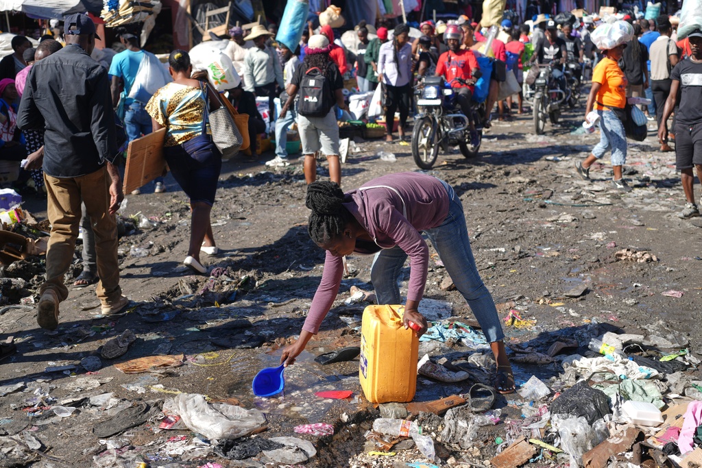 A woman collects water from a puddle in the Petion-Ville neighborhood of Port-au-Prince, Haiti, Wednesday, Feb. 11, 2026. (AP Photo/Odelyn Joseph)
