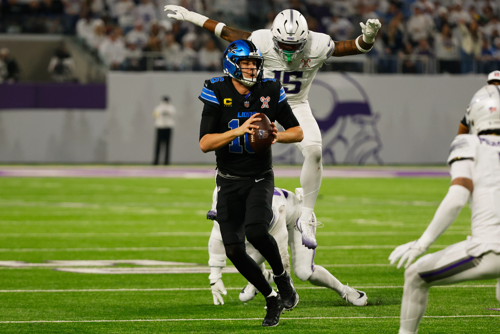 Detroit Lions quarterback Jared Goff, left, is chased by Minnesota Vikings linebacker Dallas Turner during the first half of an NFL football game, Thursday, Dec. 25, 2025, in Minneapolis. (AP Photo/Bruce Kluckhohn)