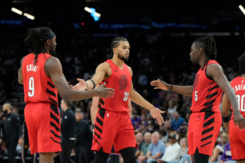 Portland Trail Blazers forward Jerami Grant (9) celebrates his 3-pointer against the Phoenix Suns with Trail Blazers forward Toumani Camara (33) and guard Jrue Holiday (5) during the first half of an NBA play-in tournament basketball game, Tuesday, April 14, 2026, in Phoenix. (AP Photo/Ross D. Franklin)