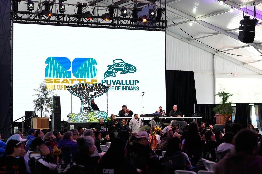 A Seattle World Cup host city logo and a Puyallup logo are seen on a large screen before a Stick-Games Tournament hosted by the Puyallup Tribe in partnership with World Cup host city Seattle, Saturday, June 27, 2026, in Tacoma, Wash. (AP Photo/Lindsey Wasson)