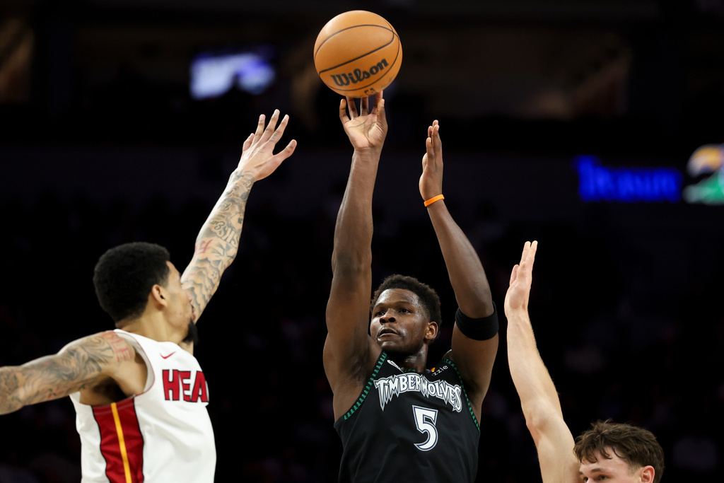 Minnesota Timberwolves guard Anthony Edwards (5) shoots between Miami Heat center Kel'el Ware, left, and guard Pelle Larsson, right, during the first half of an NBA basketball game, Tuesday, Jan. 6, 2026, in Minneapolis. (AP Photo/Ellen Schmidt)
