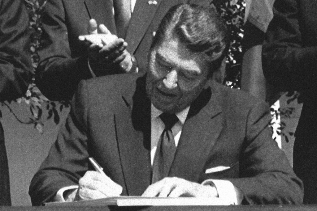 FILE - President Ronald Reagan signs legislation implementing the U.S.-Canada free trade agreement during a ceremony at the White House, Sept. 28, 1988. (AP Photo/Scott Stewart, File)