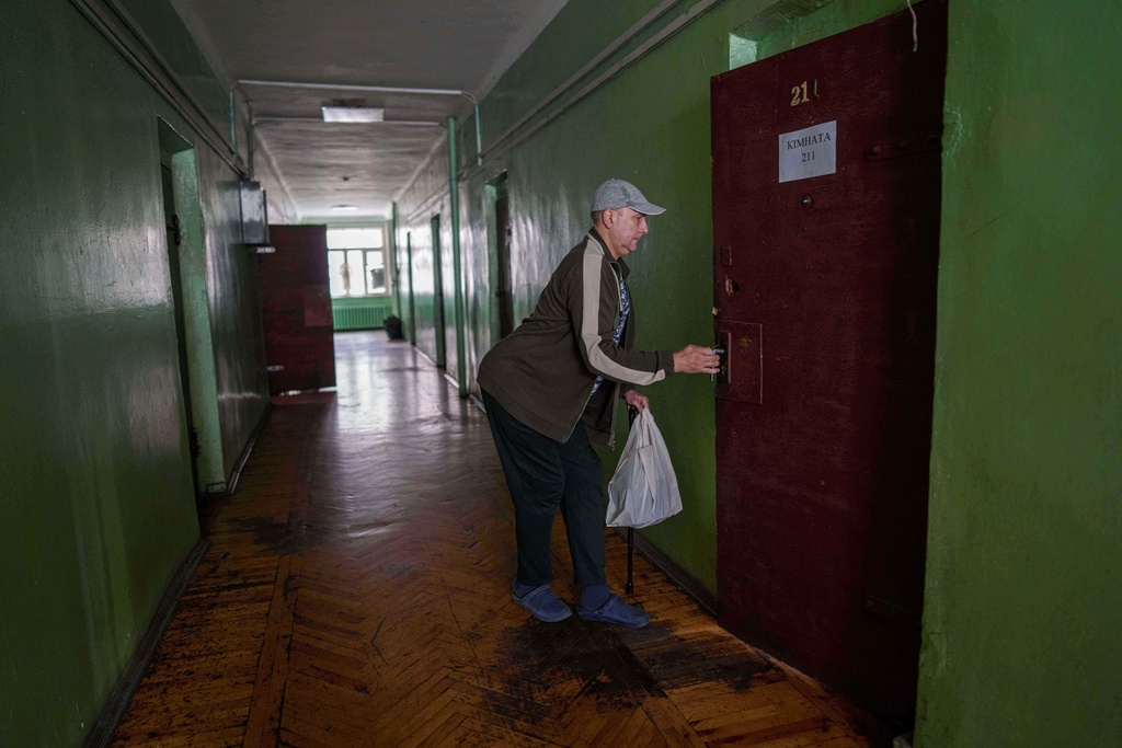 A man using a cane walks into his room at a hostel for the displaced in Dnipro, Ukraine, Wednesday, Oct. 8, 2025. (AP Photo/Evgeniy Maloletka)