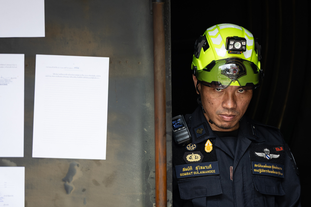 A rescuer looks on at the entrance door of the music bar where a fire killed a number of people in Bangkok, Thailand, Tuesday, July 14, 2026. (AP Photo/Wason Wanichakorn)