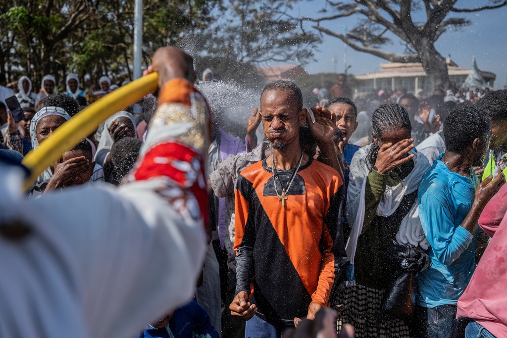 Holy water is sprayed on Ethiopian Orthodox worshippers, during the celebration of the Ethiopian Epiphany on lake Dembel, in Batu, Ethiopia, Monday, Jan. 19, 2026. (AP Photo/Amanuel Sileshi)