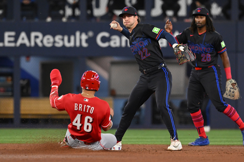 Toronto Blue Jays infielder Ernie Clement (22) throws to first base to complete a double play after forcing out Cincinnati Reds' Juan Brito (46) during the second inning of a baseball game in Toronto, Friday, Sept. 25, 2026. (Jon Blacker/The Canadian Press via AP)