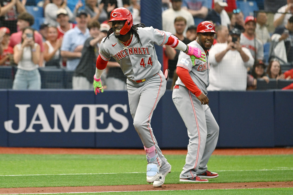 Cincinnati Reds' Elly de la Cruz (44) and third base coach Willie Harris celebrate de la Cruz's two run home run during the first inning of a baseball game against the Tampa Bay Rays Tuesday, April 21, 2026, in St. Petersburg, Fla. (AP Photo/Jason Behnken)