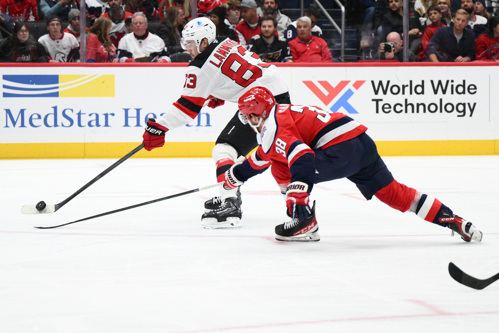 New Jersey Devils center Juho Lammikko (83) shoots against Washington Capitals defenseman Rasmus Sandin (38) during the second period of an NHL hockey game, Saturday, Nov. 15, 2025, in Washington. (AP Photo/Nick Wass)