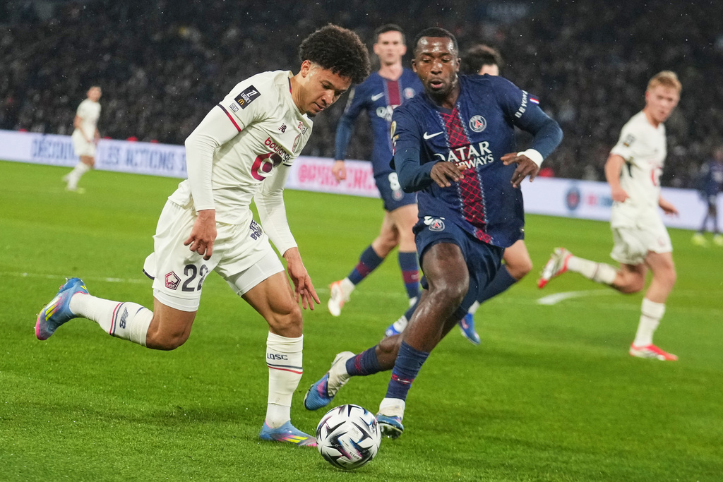 Lille's Tiago Santos, left, challenges for the ball with PSG's Willian Pacho during the French League One soccer match between Paris Saint-Germain and Lille in Paris, France, Friday, Jan. 16, 2026. (AP Photo/Michel Euler)