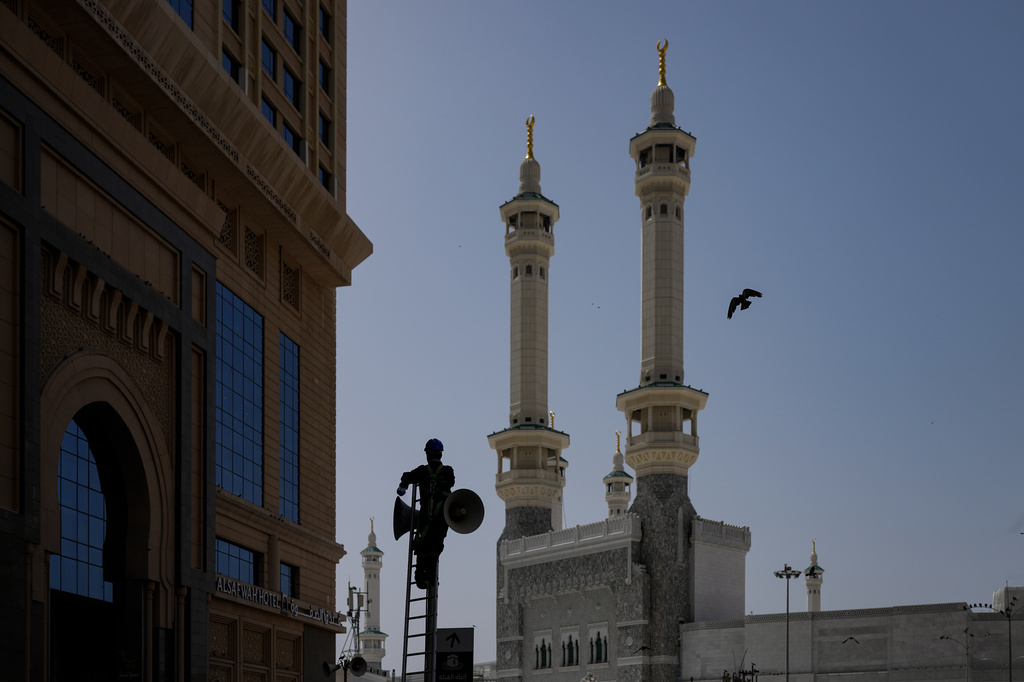 A worker is silhouetted as he cleans a speaker outside the Grand Mosque, during the annual Hajj pilgrimage in the Muslim holy city of Mecca, Saudi Arabia, Friday, May 22, 2026. (AP Photo/Altaf Qadri)