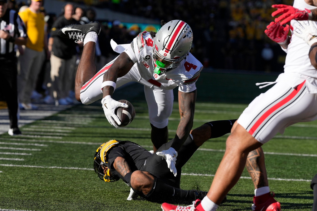 Ohio State wide receiver Jeremiah Smith (4) dives for a touchdown over Iowa defensive back Jaylen Watson during the first half of an NCAA college football game, Saturday, Oct. 3, 2026, in Iowa City, Iowa. (AP Photo/Charlie Neibergall)
