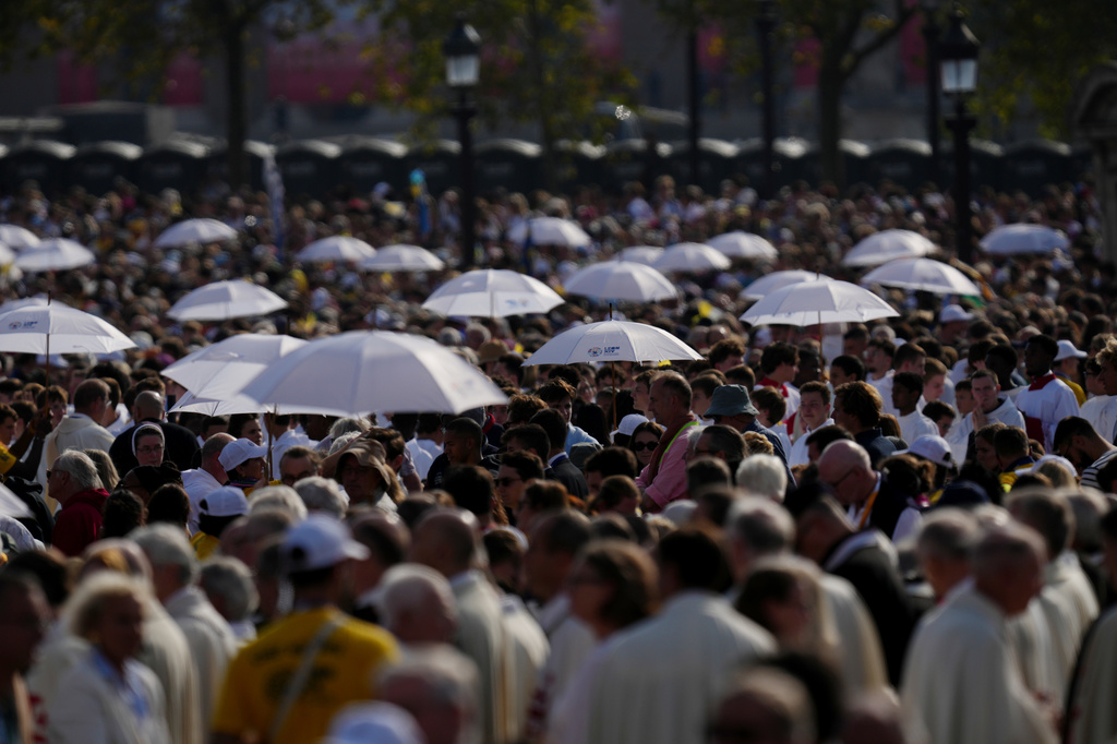 Priests hold umbrellas as they distribute the Communion as Pope Leo XIV celebrates mass at Place de la Concorde, Paris, Saturday, Sept. 26, 2026. (AP Photo/Aurelien Morissard)