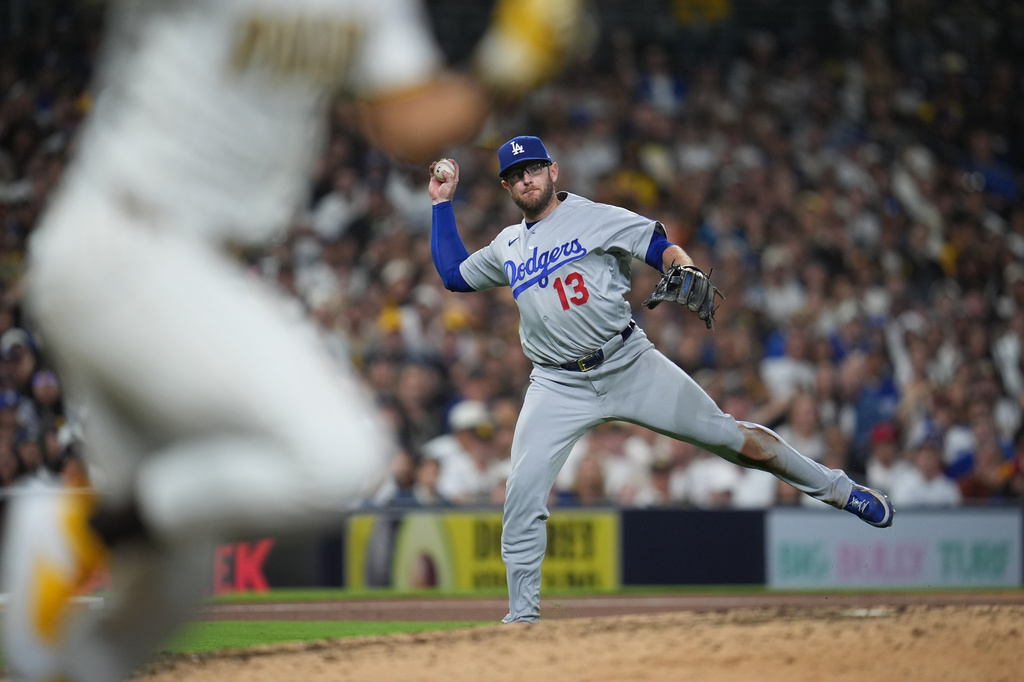 Los Angeles Dodgers third baseman Max Muncy (13) misses his throw to first as San Diego Padres' Fernando Tatis Jr. arrives safely for a single during the seventh inning of a baseball game Wednesday, May 20, 2026, in San Diego. Muncy picked up a throwing error on the play. (AP Photo/Gregory Bull)