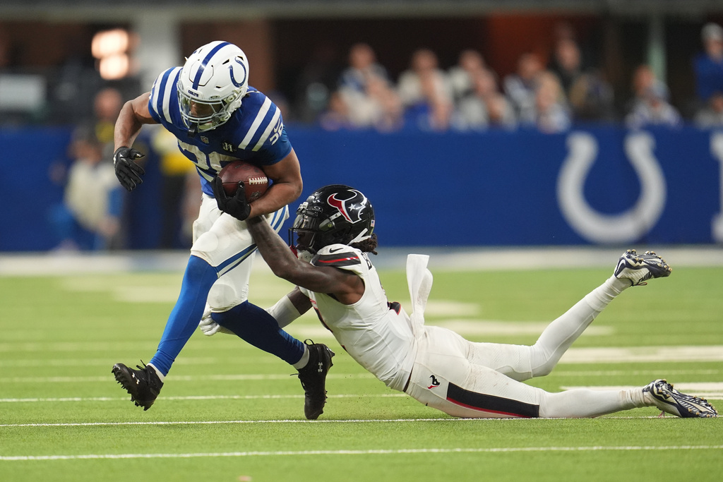 Indianapolis Colts running back Jonathan Taylor (28) is tackled by Houston Texans safety Calen Bullock (2) during the second half of an NFL football game Sunday, Nov. 30, 2025, in Indianapolis. (AP Photo/Michael Conroy)