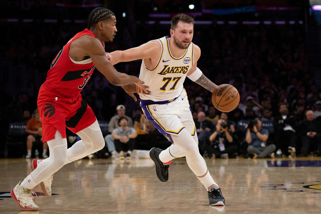 Los Angeles Lakers guard Luka Doncic (77) drives to the basket as Toronto Raptors guard Ochai Agbaji (30) defends during the first half of an NBA basketball game in Los Angeles, Sunday, Jan. 18, 2026. (AP Photo/Kyusung Gong)
