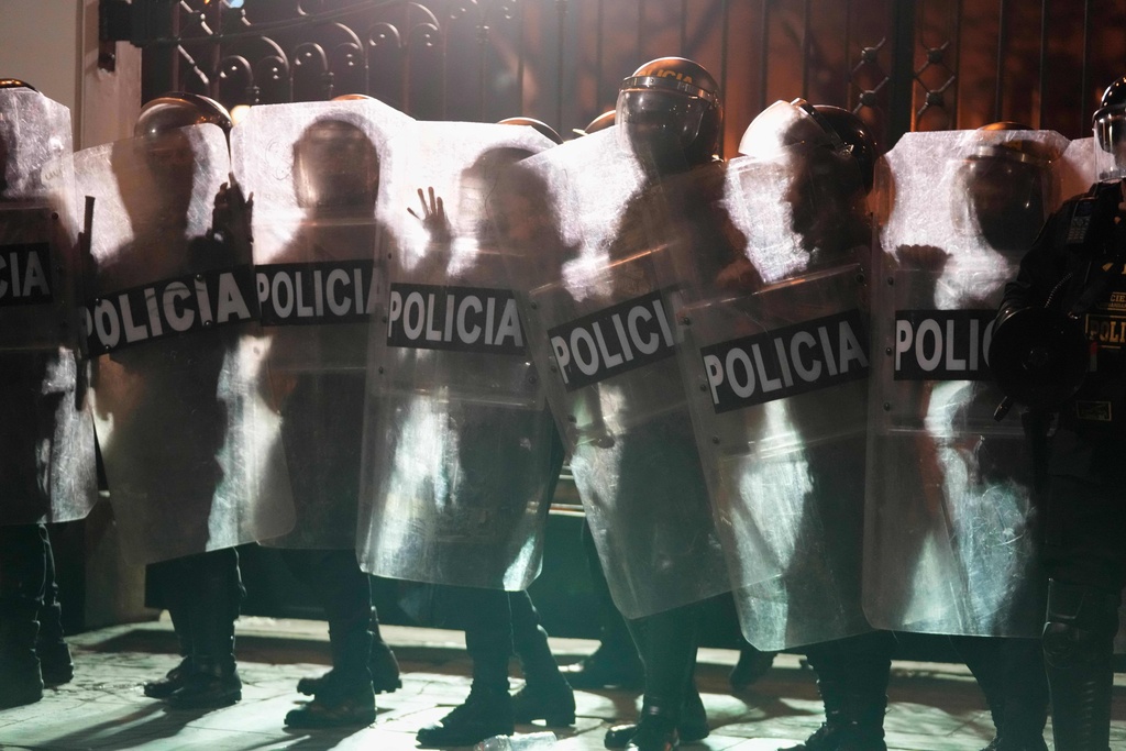 Police are silhouetted against a burning barricade as they face off with anti-government protesters during a rally against President Dina Boluarte's economic and social policies in Lima, Peru, Sunday, Sept. 28, 2025. (AP Photo/Martin Mejia)